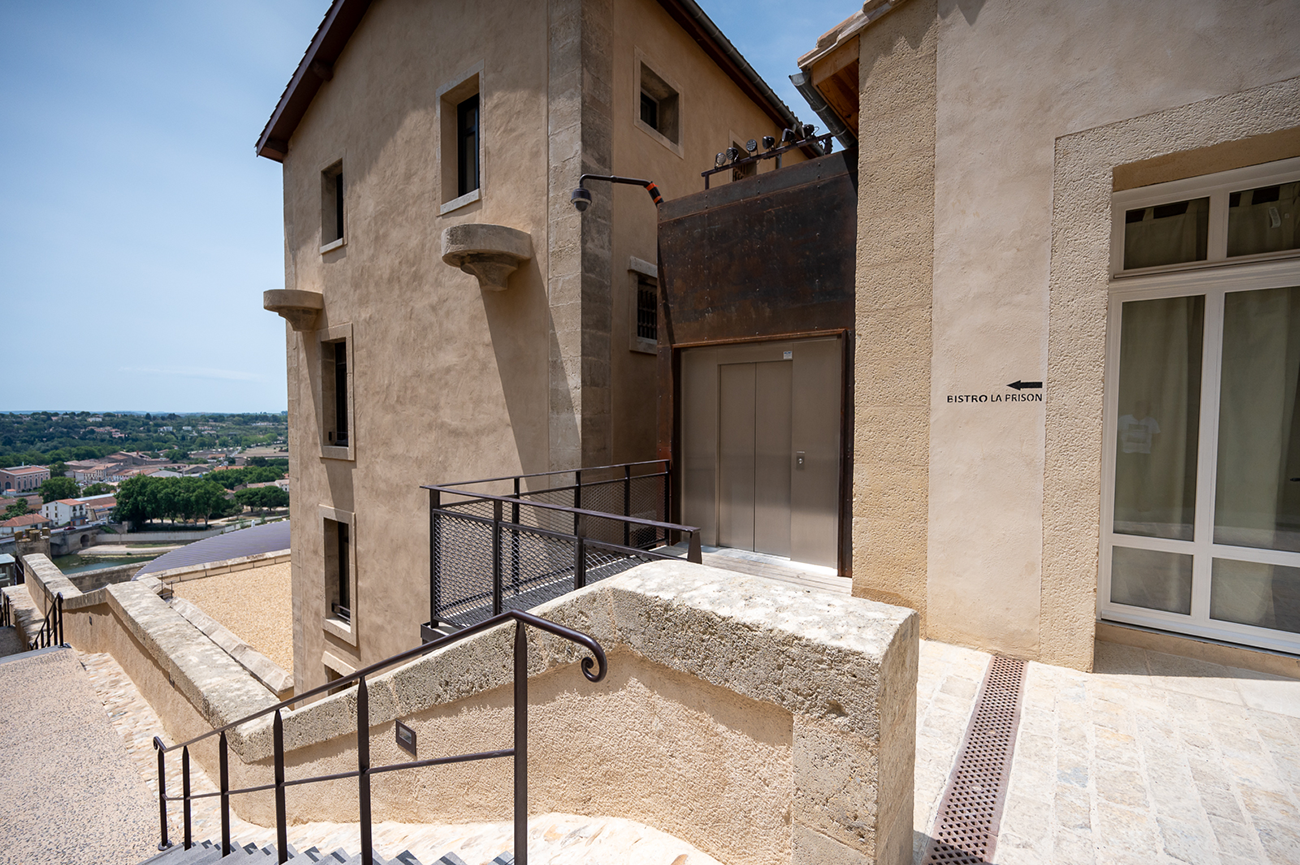 Ascenseur extérieur traversant, alliant accessibilité et mise en valeur d’un bâtiment historique.